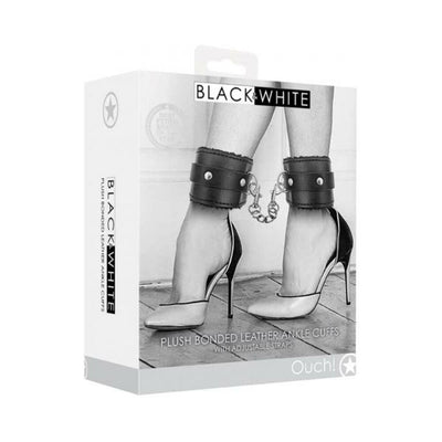 Packaging of Ouch! Black & White plush bonded leather ankle cuffs with adjustable straps shown on model wearing high heels.