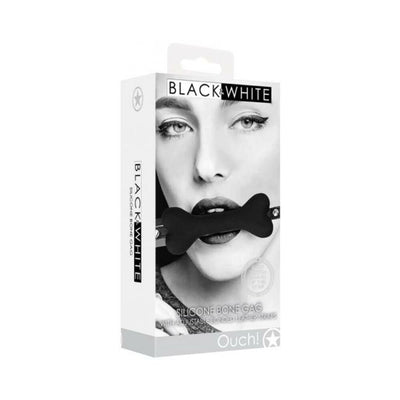 Packaging of Ouch! Black & White silicone bone gag with adjustable bonded leather straps shown on a model in black and white design.