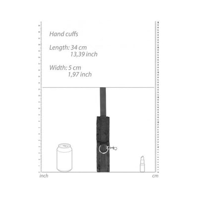 Black and white velcro hand cuff with metal ring and clip, shown with size measurements and comparison to a soda can and lipstick.