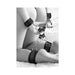 Black and white velcro hogtie with furry hand and ankle cuffs connected by metal rings on a seated person.