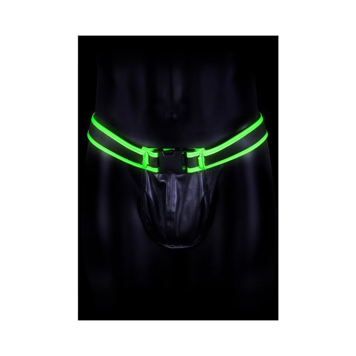 Black jock strap with glowing green buckle and straps on a dark mannequin torso.
