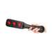 Hand holding black leather paddle with three red heart cutouts for playful imprinting.