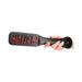 Hand holding black leather paddle with red "SPANK" cutout lettering on paddle face against white background.
