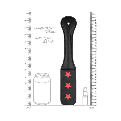 Black leather paddle with three red star cutouts, shown with measurement scale and size comparison to a soda can and lipstick.