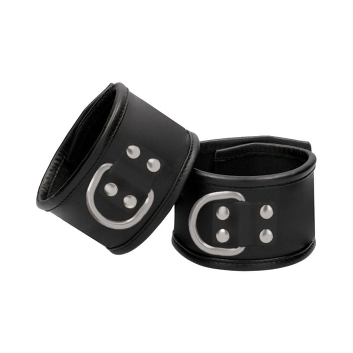 Black saddle leather handcuffs with metal D-rings and padded interior for comfort and secure restraint.