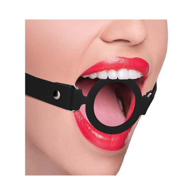 Close-up of a person wearing a black silicone ring gag with adjustable leather straps and red lipstick.