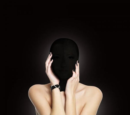 Person wearing a black stretchy subjugation mask covering the entire head with hands gently touching the face.