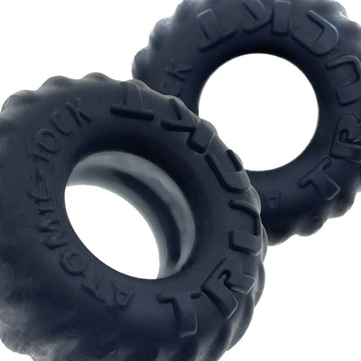 Two black silicone cockrings with tire tread texture and embossed "TRUCKT" branding on a white background.