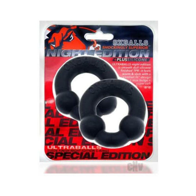 Two black Oxballs Ultraballs Night Edition cockrings with dual nodules in clear retail packaging on red and black background.