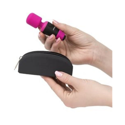 Hands holding a pink Palm Power Pocket Massager and a small black zippered storage case against a white background.