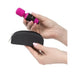 Hands holding a pink Palm Power Pocket Massager and a small black zippered storage case against a white background.