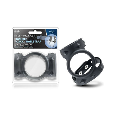 Black silicone double cock and ball strap with adjustable snaps, shown in and out of packaging.