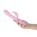 Hand holding a pink Pillow Talk Lively Dual Stimulator with textured shaft and curved clitoral attachment.