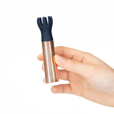 Hand holding a navy silicone tickler head mini massager with a textured rose gold base against a white background.