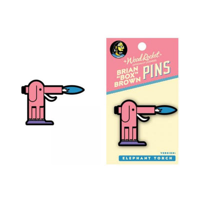 Pink elephant-shaped torch enamel pin with blue flame, displayed on branded backing card by Brian "Box" Brown.