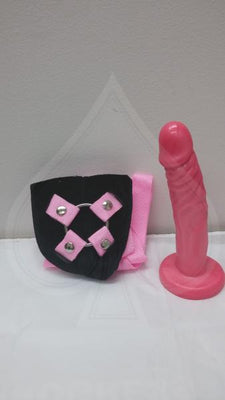 Pink adjustable harness with 7.5 inch realistic pink dong and secure snap closures on black padded base.