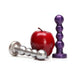 Two bead-style anal plugs in metallic silver and midnight purple next to a red apple for size comparison on a white background.