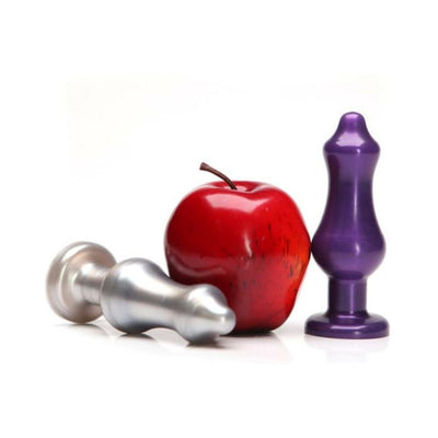 Two silicone butt plugs in metallic silver and purple colors displayed next to a red apple for size comparison.