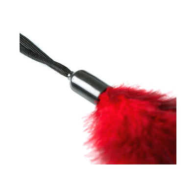 Close-up of a red feather tickler with a black handle and wrist cord on a white background.