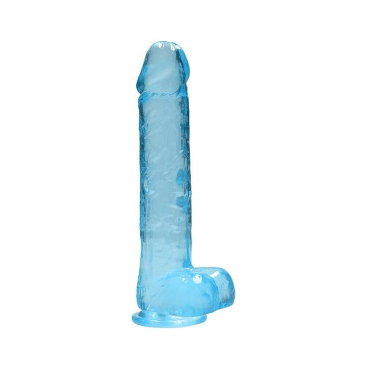 Blue crystal clear realistic dildo with balls and suction base standing upright on white background.
