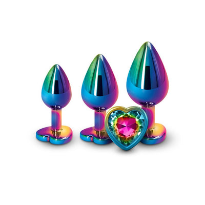 Three graduated rainbow-colored metal trainer plugs with a heart-shaped jeweled base on a white background.
