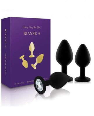 Set of three black silicone booty plugs with gem-like stone bases displayed next to purple Rianne S packaging box.