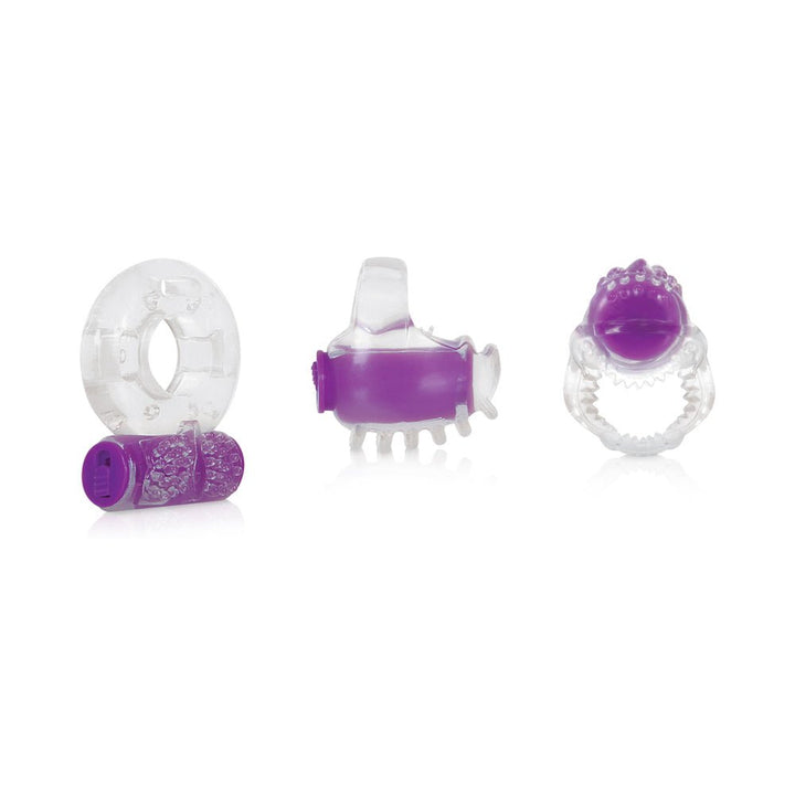 Three clear and purple vibrating pleasure rings with textured designs in a 3-piece kit on a white background.