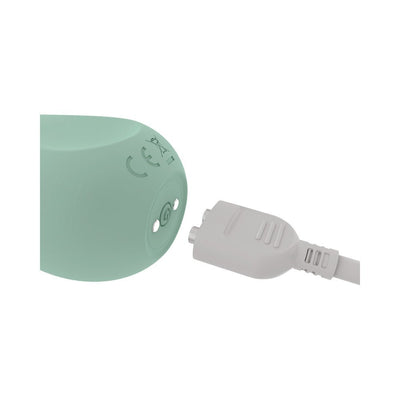 Close-up of mint green Ritual Chi rechargeable silicone clitoral vibrator with magnetic USB charging cable.