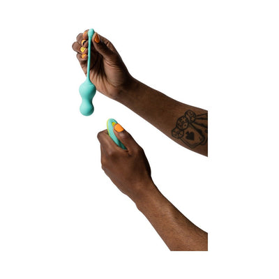 Hands holding a light teal silicone G-spot vibrator and matching remote control against a white background.