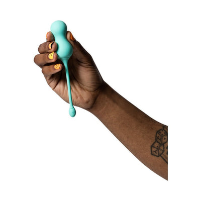 Hand holding a light teal silicone G-spot egg vibrator with a long tail and power button detail.