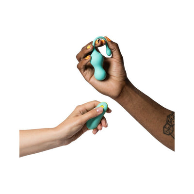 Hands holding a light teal ROMP Cello rechargeable silicone G-spot vibrator and its remote control against a white background.