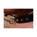 Close-up of a black studded leather collar with a silver O-ring worn around a neck.