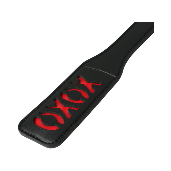 Black vinyl paddle with red XOXO cutout design and stitched edges, angled view on white background.