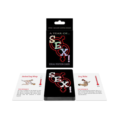 A Year of SEX! card game box with a deck of illustrated sexual position cards, showing two example cards with techniques and intensity ratings.