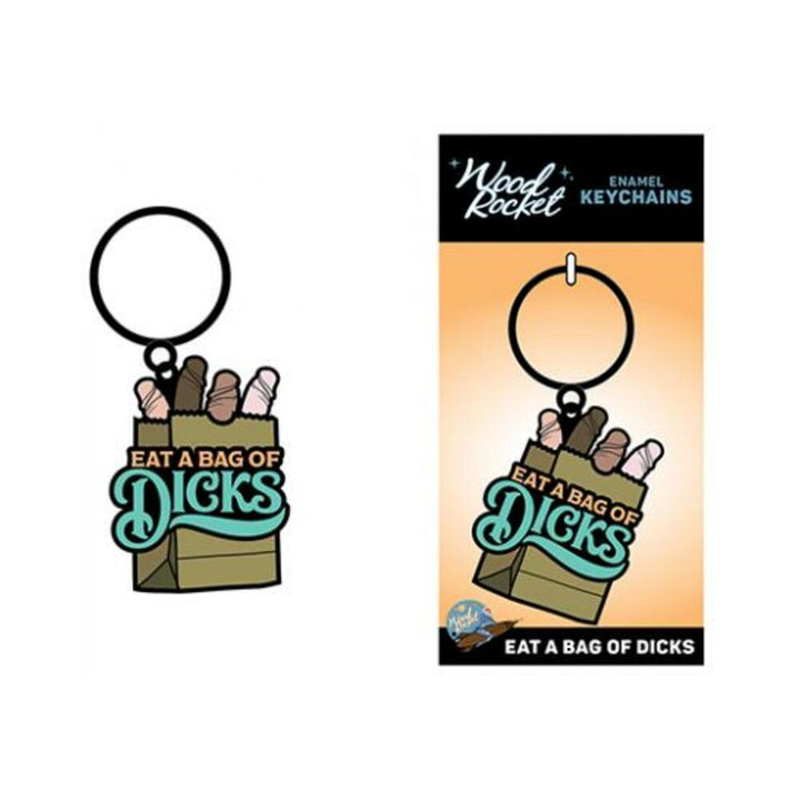 Enamel keychain featuring a paper bag with playful text "Eat a Bag of Dicks" and colorful shapes inside, attached to a black key ring.