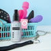 Sextoy Body & Toy Cleaner 4 oz spray bottle with a basket of colorful intimate toys and accessories on a light blue background.