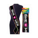 Black party sash with "SHE + HER" in white letters and a pink heart, edged with rainbow trim, displayed on a mannequin and in packaging.
