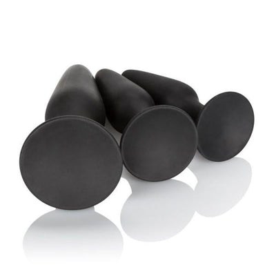 Three black silicone anal trainers in small, medium, and large sizes with flared bases, arranged on a white reflective surface.