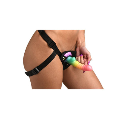 Close-up of a person wearing a black adjustable harness with a ribbed rainbow silicone dildo attached.