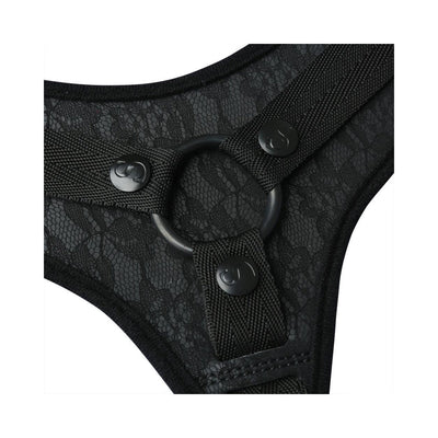 Close-up of black lace strap-on harness featuring adjustable nylon straps and a central O-ring detail.
