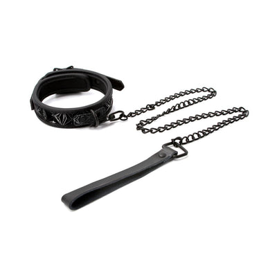 Black adjustable collar with embossed design and attached chain leash with leather handle on white background.