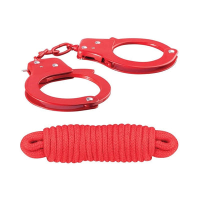 Red metal handcuffs with keys and a neatly coiled red cotton rope on a white background