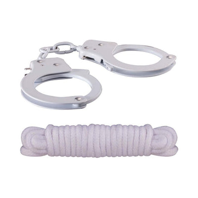 Silver metal handcuffs with keys and a neatly coiled white cotton rope on a white background.