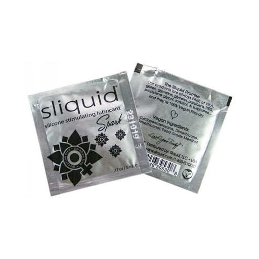 Two silver foil packets of Sliquid Naturals Spark silicone stimulating lubricant, showing front and back packaging details.