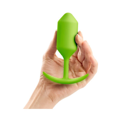 Hand holding a bright green weighted silicone plug with a flexible neck and curved base.