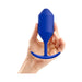 Hand holding a blue silicone weighted snug plug with a tapered tip and curved base for comfortable use.