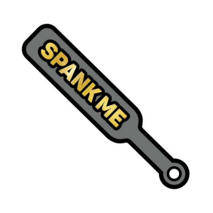 Gray enamel paddle pin with gold "SPANK ME" text and black outline, shaped like a mini BDSM paddle accessory.