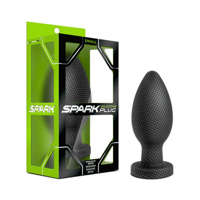Small carbon fiber textured silicone plug with tapered tip and suction cup base next to green and black Spark branded packaging.
