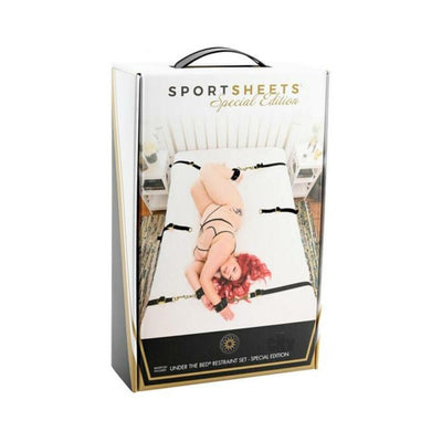 Special Edition Under the Bed Restraint Set packaging showing adjustable black straps and cuffs on a white mattress with a model in lingerie.