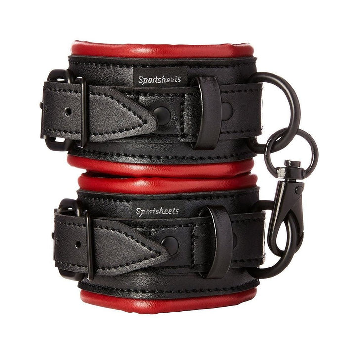 Pair of black and red padded vegan leather Sportsheets Saffron adjustable handcuffs with metal clasps and D-rings.